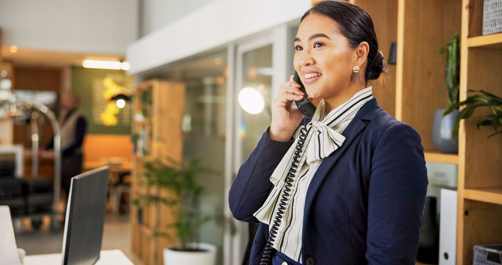 Web_Wide-Woman, phone call and happy at hotel, concierge and talk with client for booking information. Person, help desk and receptionist with teleph